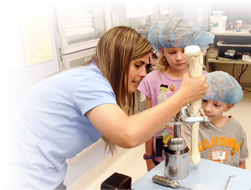 Nurse showing children sawbone surgery demo